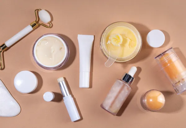 Flat-lay beauty products including face creams, serums, oils, and jade roller on beige background for beauty influencer content