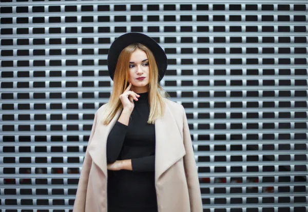 Female influencer in black crop top and cream cardigan against geometric brick wall for brand campaign