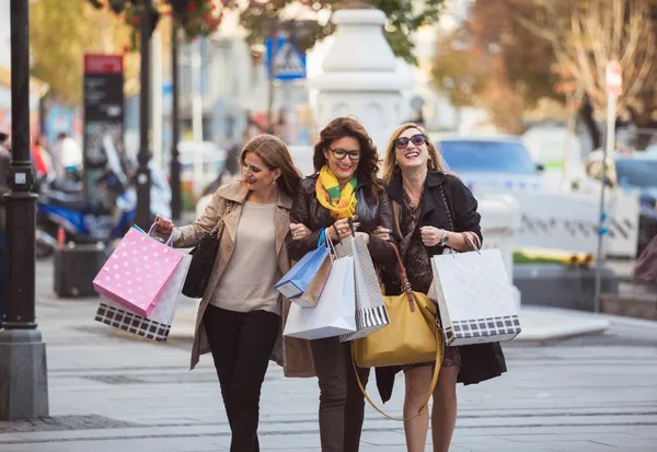 Three women shopping with colorful bags on city street, lifestyle influencer content