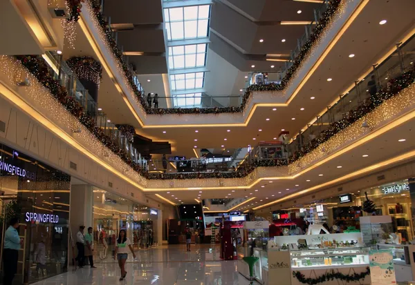 Multi-level shopping mall with golden holiday decorations and retail stores - influencer shopping content location