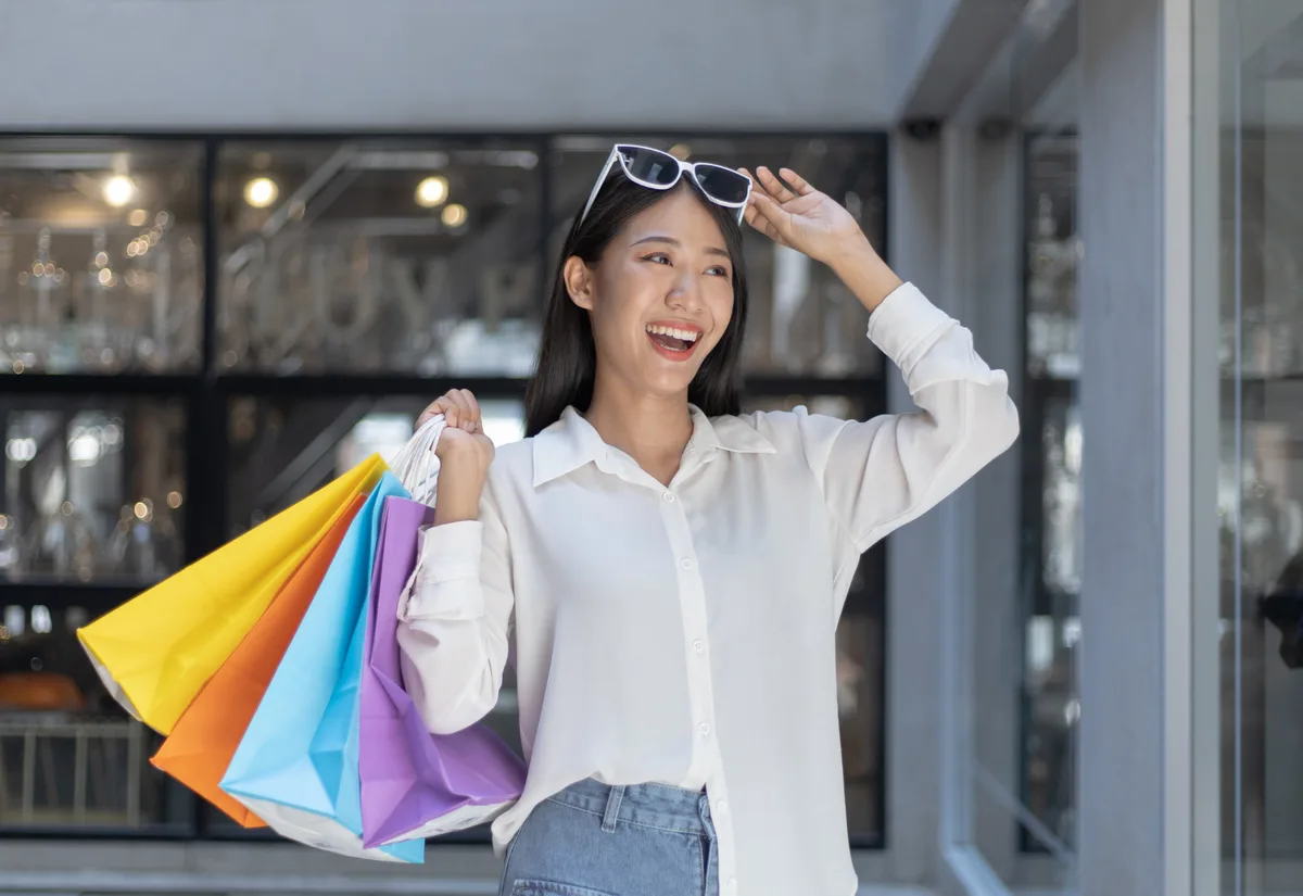 Smiling woman with shopping bags at store, influencer lifestyle content